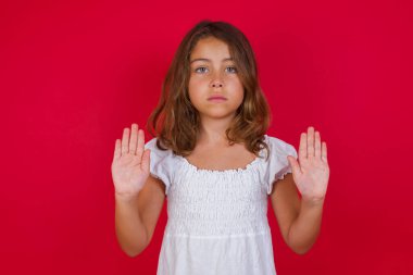 Güzel mavi gözlü küçük beyaz kız dur hareketi yapıyor, duygularını kontrol etmek ve gergin olmamak istiyor.