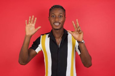 Genç adam kendini beğenmiş ve mutlu bir şekilde gülümseyerek sekiz numarayı işaret ediyor..