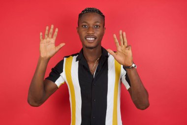 Genç adam kendini beğenmiş ve mutlu bir şekilde gülümserken dokuz numarayı işaret ediyor..