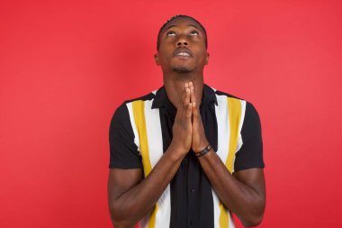 Genç adam elleri bağlı yalvarıyor ve dua ediyor. Yüzünde umut ifadesi var. Çok duygusal ve endişeli. Soruyorum.