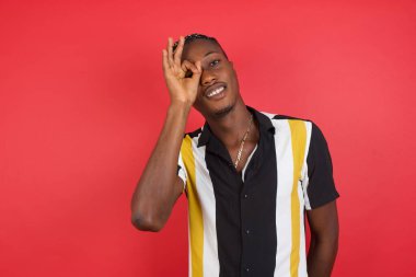 Yakışıklı genç adam el hareketleriyle gülümsüyor, gözleriyle mutlu yüzüyle parmaklarından bakıyor..