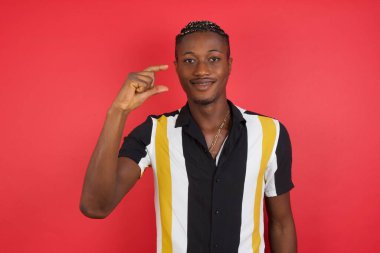 Yakışıklı genç adam el hareketleriyle küçük boy işareti yapıyor parmakları bakıyor ve kameraya bakıyor. Ölçü kavramı