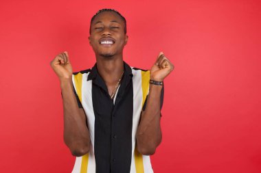 Yakışıklı genç adam zafer kutlamaları için kollarını kaldırarak ve gözlerini kapatarak başarı için heyecanlanıyor. Kazanan konsept.