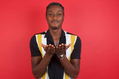 Yakışıklı genç adam avuçlarını açıp kameraya bir şey sunuyor..