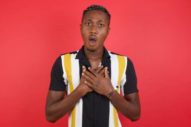 Korkmuş ifadeli genç yakışıklı adam ellerini göğsünde tutuyor. Garip bir şey fark edince kafası karışıyor. Sessiz tepki ve duygular..