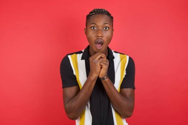 Elleri yüzü çaprazlanmış, şans dilemek için dua eden genç adam şaşırmış ve ağzı açık bir şekilde önüne bakıyordu..