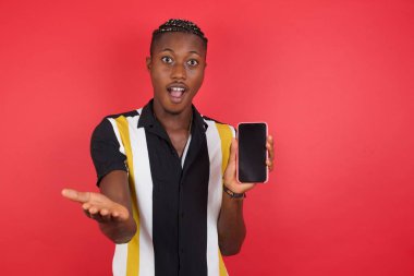 Kırmızı stüdyo arka planında akıllı telefon kullanan genç yakışıklı adam.