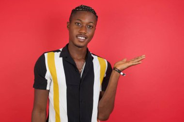 Yakışıklı genç adam kameraya bakarak avucunu gösteriyor..