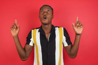 Genç adam yukarı bakıyor ve parmaklarıyla ve kollarıyla işaret ediyor..