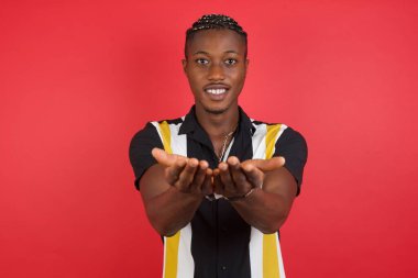 Elleri avuçlarında gülümseyen genç adam el hareketi yapıyor ya da yapıyor. Tutun ve koruyun