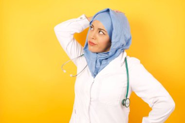 Sarı stüdyo arka planında steteskobu olan güzel bir kadın Arap doktor.