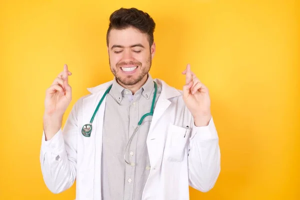 正の白人医師の写真男は大きな希望を持って 指を横断し 医療制服を着て 幸運を信じて 黄色の背景に隔離された笑顔 人と願いの概念 — ストック写真