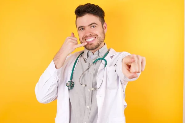 Młody Przystojny Biały Lekarz Mundurze Medycznym Uśmiecha Się Wesoło Wskazuje — Zdjęcie stockowe