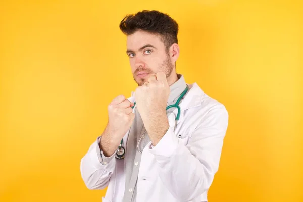 Joven Médico Caucásico Vestido Uniforme Médico Pie Sobre Fondo Amarillo — Foto de Stock