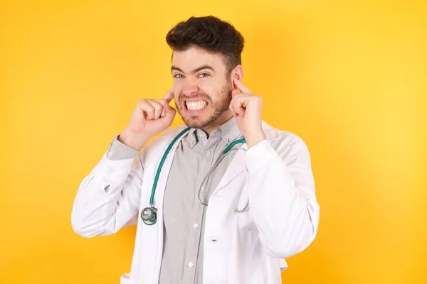 Νεαρός Ευρωπαίος Όμορφος Γιατρός Ιατρική Στολή Που Καλύπτει Αυτιά Δάχτυλα — Φωτογραφία Αρχείου