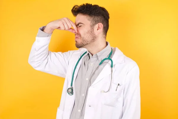 Bonito Jovem Médico Vestindo Uniforme Médico Sobre Fundo Amarelo Isolado — Fotografia de Stock