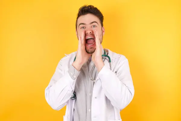 Joven Médico Caucásico Vestido Uniforme Médico Sobre Fondo Amarillo Gritando — Foto de Stock