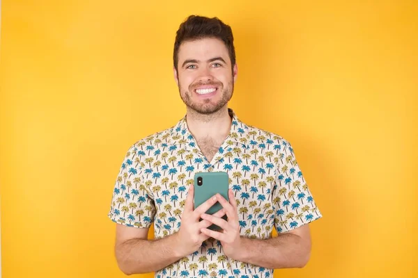 Fotografie Okouzlujícího Mladého Muže Chytrým Telefonem Pózující Pozadí Studiové Stěny — Stock fotografie