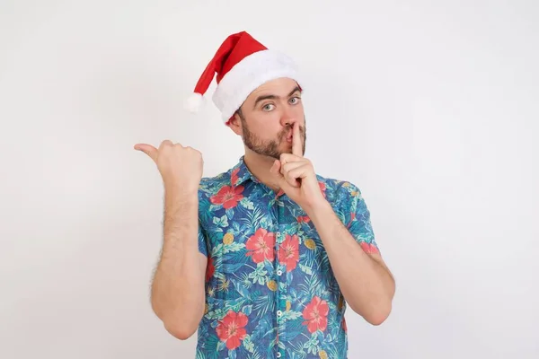 Noel Baba Şapkalı Genç Adam Sessiz Olmak Istiyor Parmaklarını Dudaklarına — Stok fotoğraf