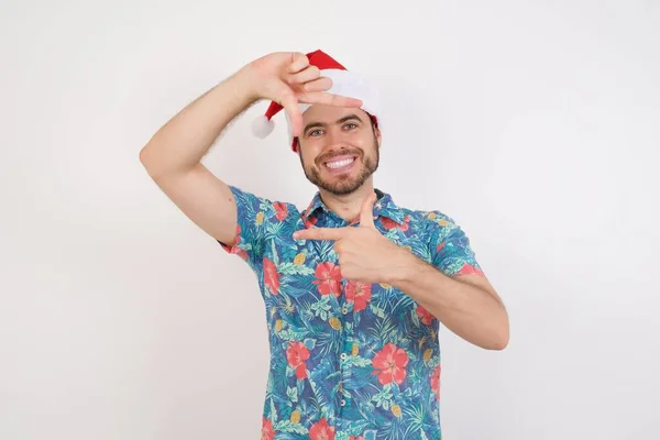 Noel Baba Şapkalı Genç Adam Elleriyle Parmak Çerçevesi Yapıyor Yaratıcılık — Stok fotoğraf