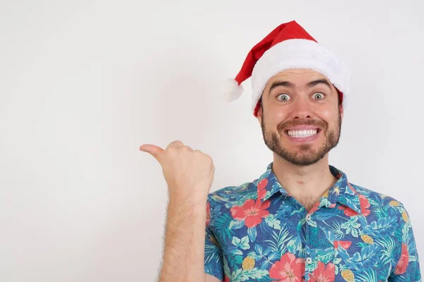 Noel Baba Şapkalı Genç Adam Işaret Parmağıyla Fotokopi Uzayını Gösteriyor — Stok fotoğraf