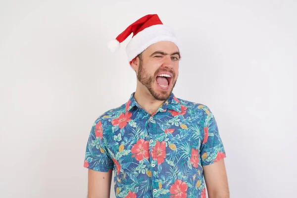 Junger Mann Mit Weihnachtsmütze Zwinkert Die Kamera Mit Sexy Gesichtsausdruck — Stockfoto