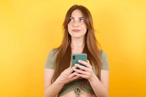 Beautiful Young Woman Posing Modern Smartphone Yellow Studio Background — Stock Photo, Image