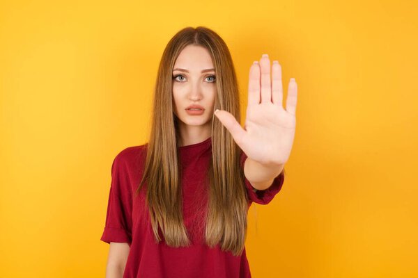 Beautiful young woman doing stop gesture with palm of the hand. Warning expression with negative and serious gesture on the face 