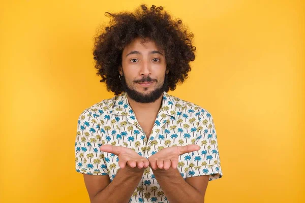 handsome young man holding something with open palms, offering to the camera.