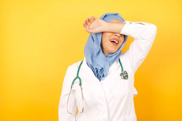 Νεαρή Γυναίκα Γιατρός Φορώντας Ιατρική Στολή Καλύπτει Μάτια Χέρι Χαμογελώντας — Φωτογραφία Αρχείου