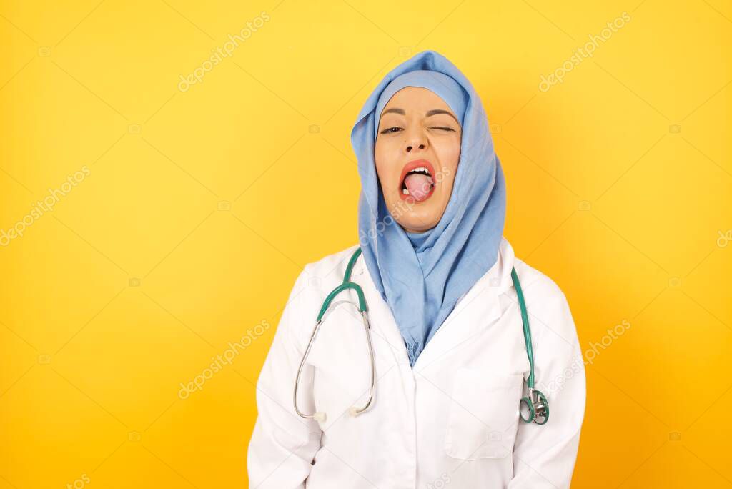 Young female doctor wearing medical uniform  sticking tongue out happy with funny expression. Emotion concept.