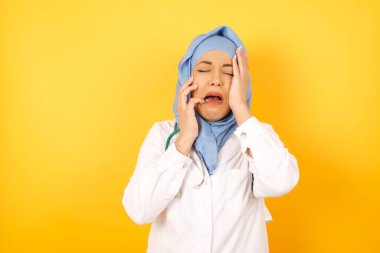 Sarı stüdyo arka planında steteskobu olan güzel bir kadın Arap doktor.