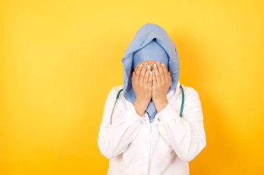 Sarı stüdyo arka planında steteskobu olan güzel bir kadın Arap doktor.