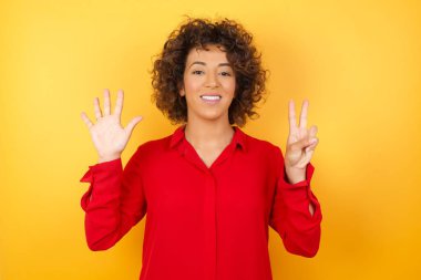 Güzel genç bir kadın 7 numaralı parmaklarıyla gülümseyerek kendini güvende ve mutlu hissediyor..