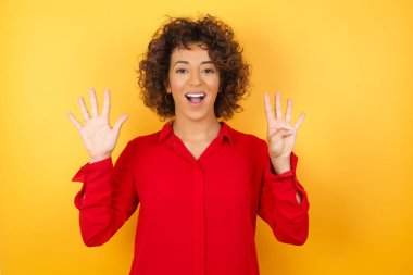 Güzel genç bir kadın dokuz numaralı parmaklarıyla gülümseyerek kendini güvende ve mutlu hissediyor..