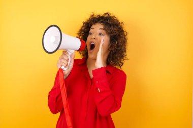 young woman with megaphone shouting and screaming loud to side with hand on mouth. Communication concept. clipart