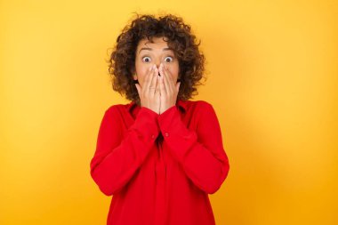 Güzel genç bir kadın neşe içinde kıkırdıyor, ağzını kapatıyor, tek başına eğleniyor, sarı arka plan ya da stüdyo duvarına yaslanıyor, doğal kahkahaları var, olumlu hikayeler duyuyor ya da komik anekdotlar dinliyor.