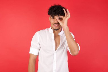 Genç yakışıklı adam el hareketleriyle gülümsüyor, gözleriyle mutlu yüzüyle parmaklarından bakıyor..