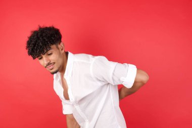 Sırt ağrısından muzdarip genç, yakışıklı bir adam, elleriyle dokunuyor, kasları ağrıyor.