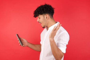 Stüdyoda kırmızı duvar, cep telefonuyla karışık ırk adamı, video görüşmesi. 