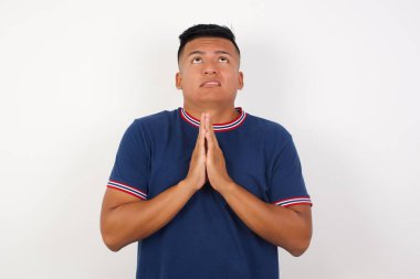 Yakışıklı genç adam elleri bağlı yalvarıyor ve dua ediyor. Yüzünde umut ifadesi var. Çok duygusal ve endişeli. Soruyorum.