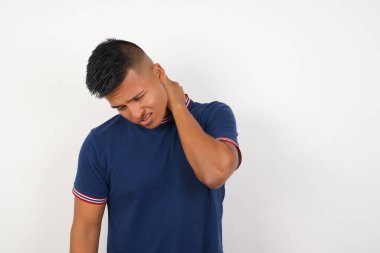 Yakışıklı genç bir adam boynu ağrıyor. Boynuna elinle dokunuyor. Kas ağrısı var.
