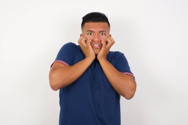 Yakışıklı genç adam heyecan ve heyecan ifade eder, çenesini indirir, elleri yanaklarında, gözleri fırlar