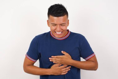 Genç ve yakışıklı bir adam yüksek sesle gülümsüyor ve gülüyor çünkü elleri vücutta komik bir şaka var..