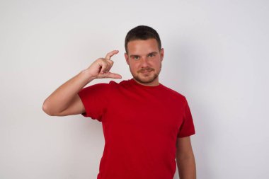 Adam gülümsüyor ve küçük boy gösteriyor, el hareketleriyle küçük boy işareti yapıyor, parmaklarıyla bakıyor ve kameraya bakıyor. Ölçü kavramı