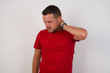 Boynu ağrıyan bir adam, eliyle boynuna dokunuyor, kasları ağrıyor.