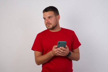 Kafkasyalı adamın fotoğrafı cep telefonu kullanıyor, akıllı telefon tutuyor ve stüdyoya bakıyor. 