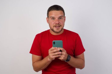 Beyaz adamın fotoğrafı cep telefonu kullanıyor, akıllı telefonu tutuyor ve kameraya bakıyor. 