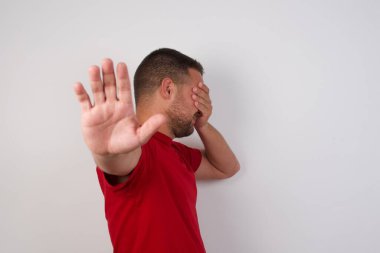 Adam elleriyle gözlerini kapatır ve jest yapar, saklanmaya çalışır. 