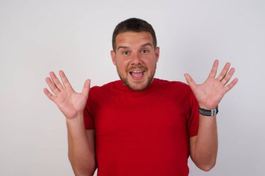 İyimser adam arka planda izole edilmiş kırmızı gömlekli mutlu bir şekilde bağırıyor.